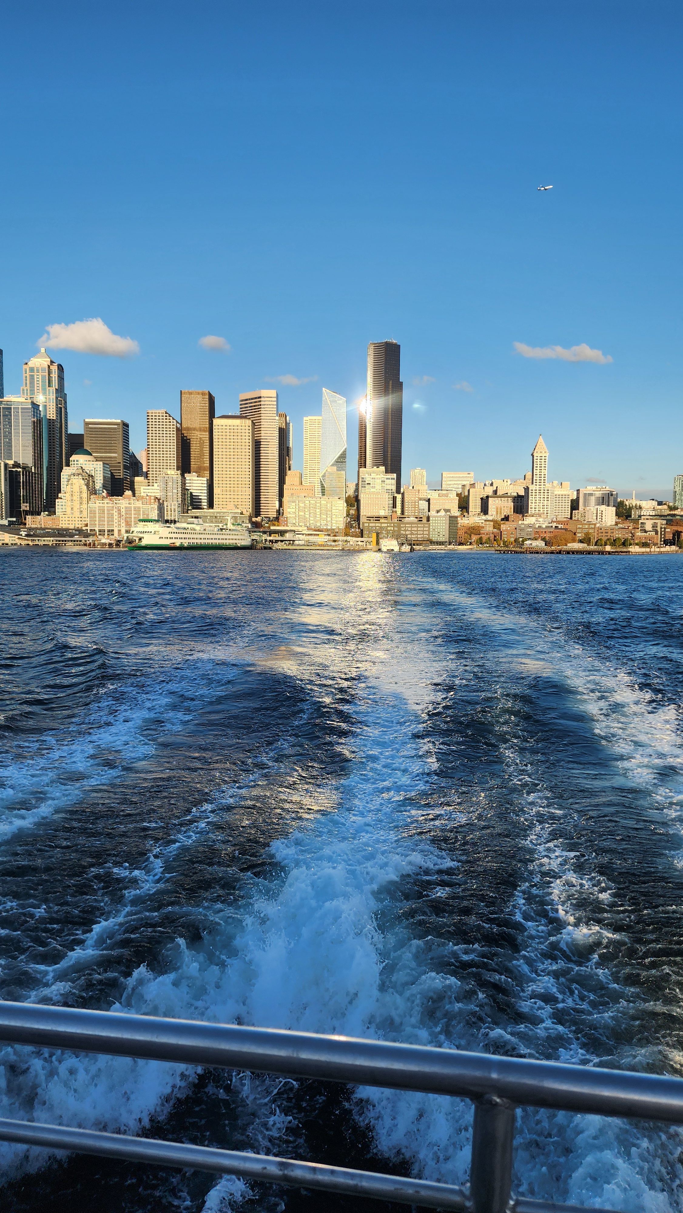 Wake of a boat leading toward a Seattle skyline in the distance.