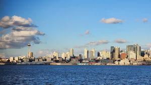 Seattle skyline across the water under scattered clouds.