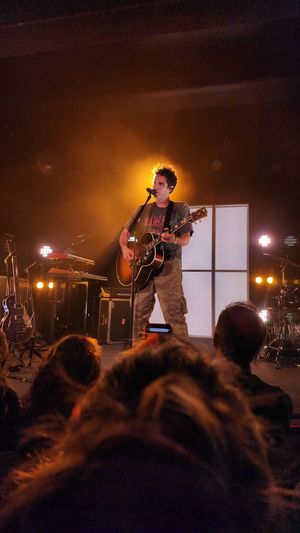 Singer on stage with spotlight, viewed from the audience.