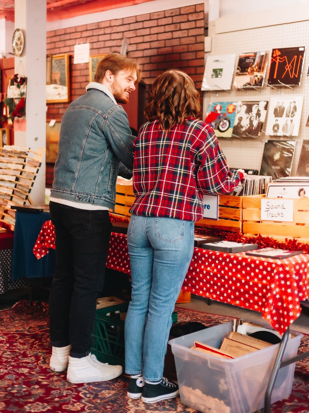 A couple explores a vintage record store with red polka dot decorations.