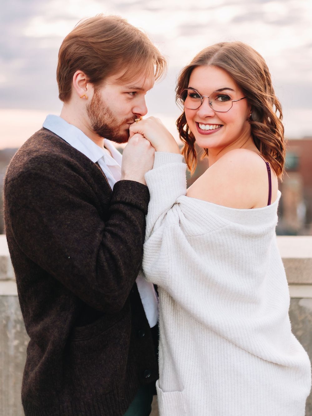 A couple shares an intimate moment wearing cozy winter clothing on a rooftop.