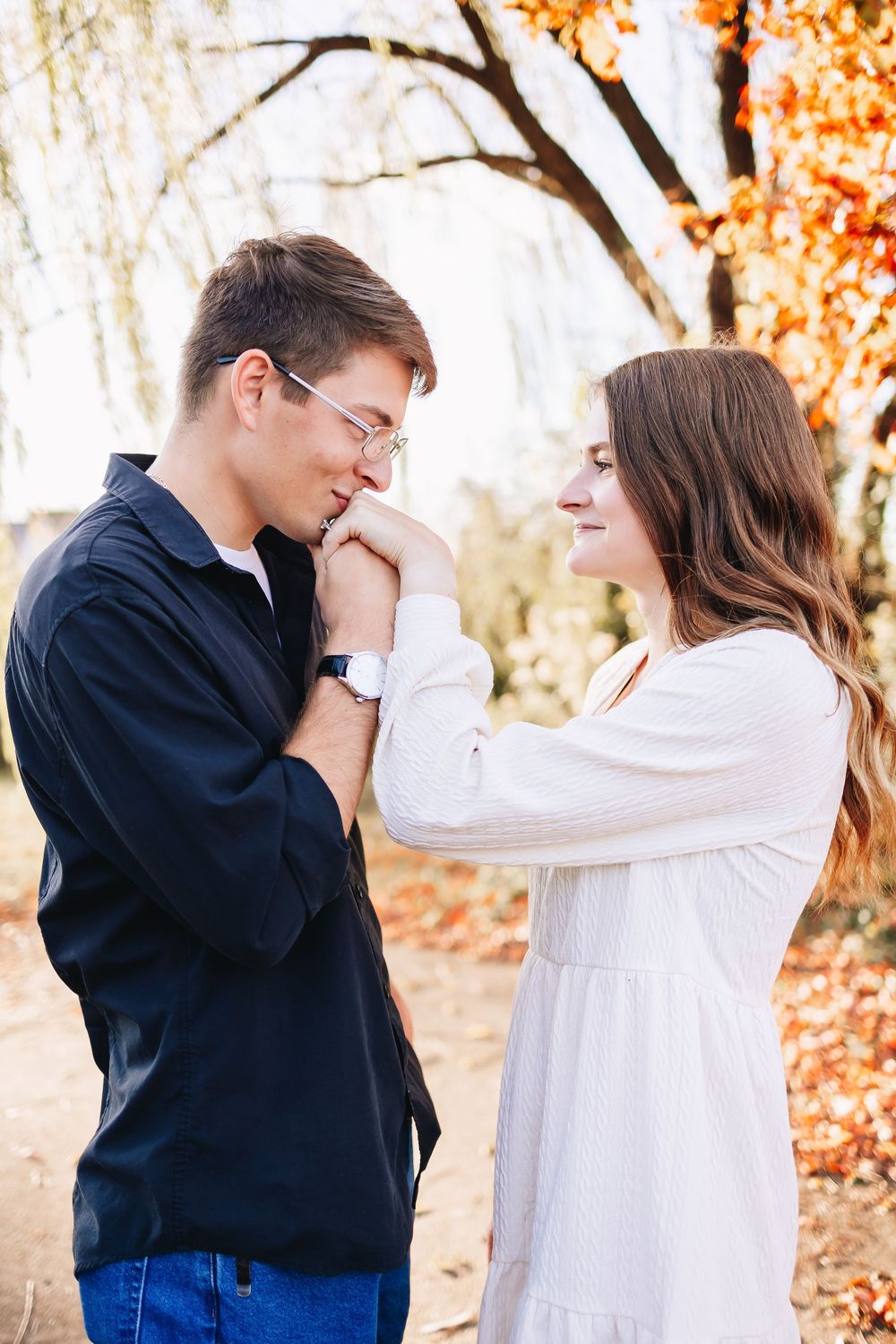 Tender moment between couple in autumn setting with fall foliage.