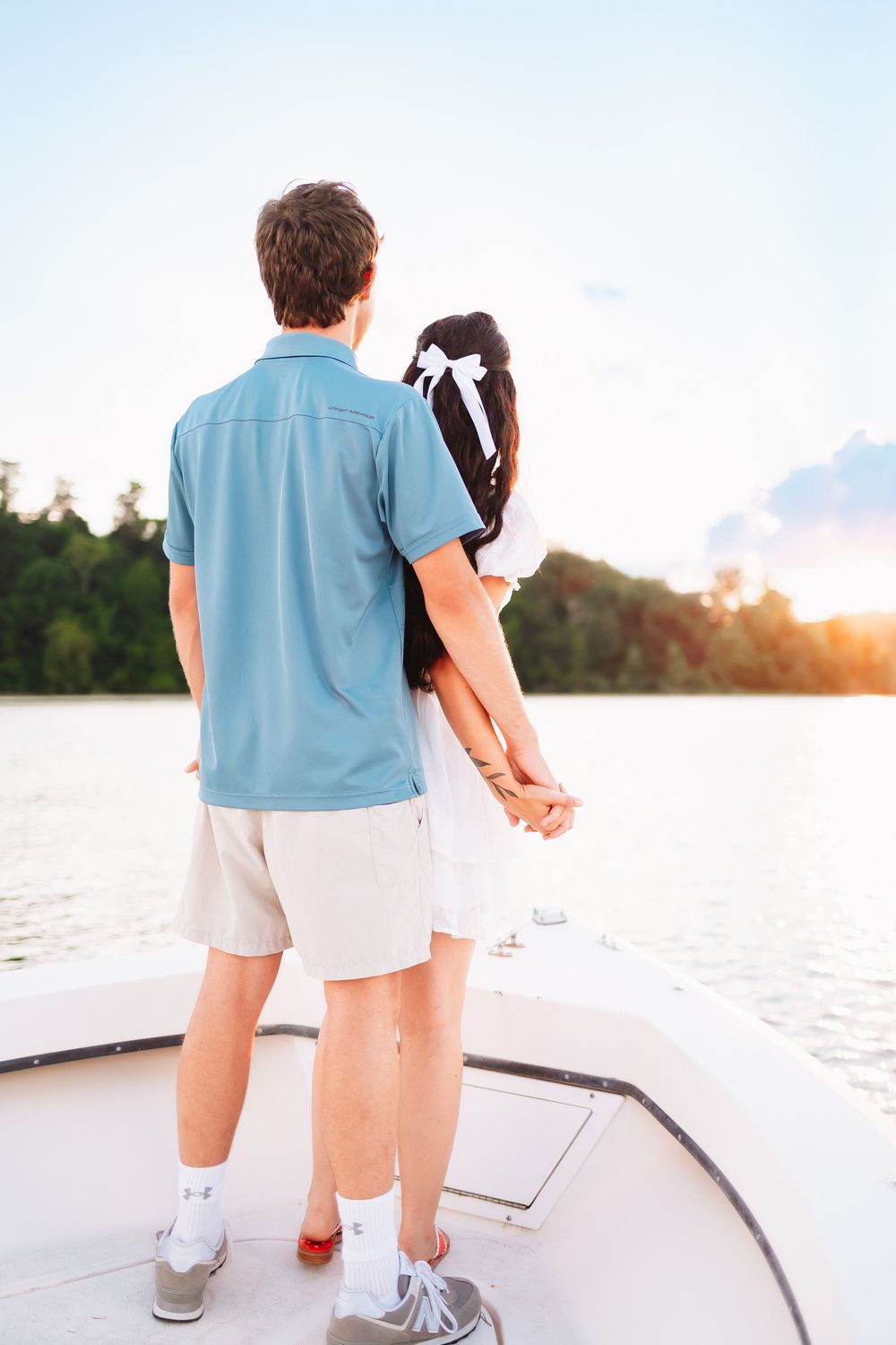 Couple standing together on boat deck during sunset over water.