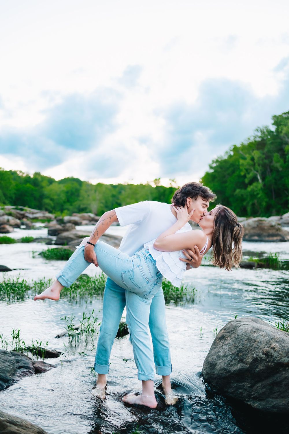 Romantic couple sharing intimate moment on rocks by flowing river.