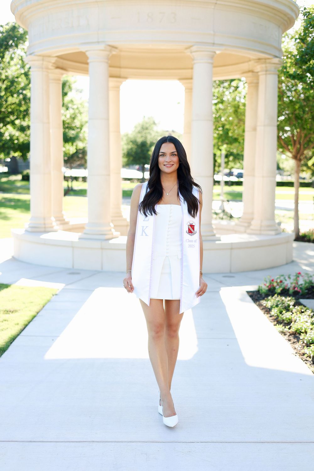 A white columned pavilion provides an elegant backdrop for a photo session on a sunny day.
