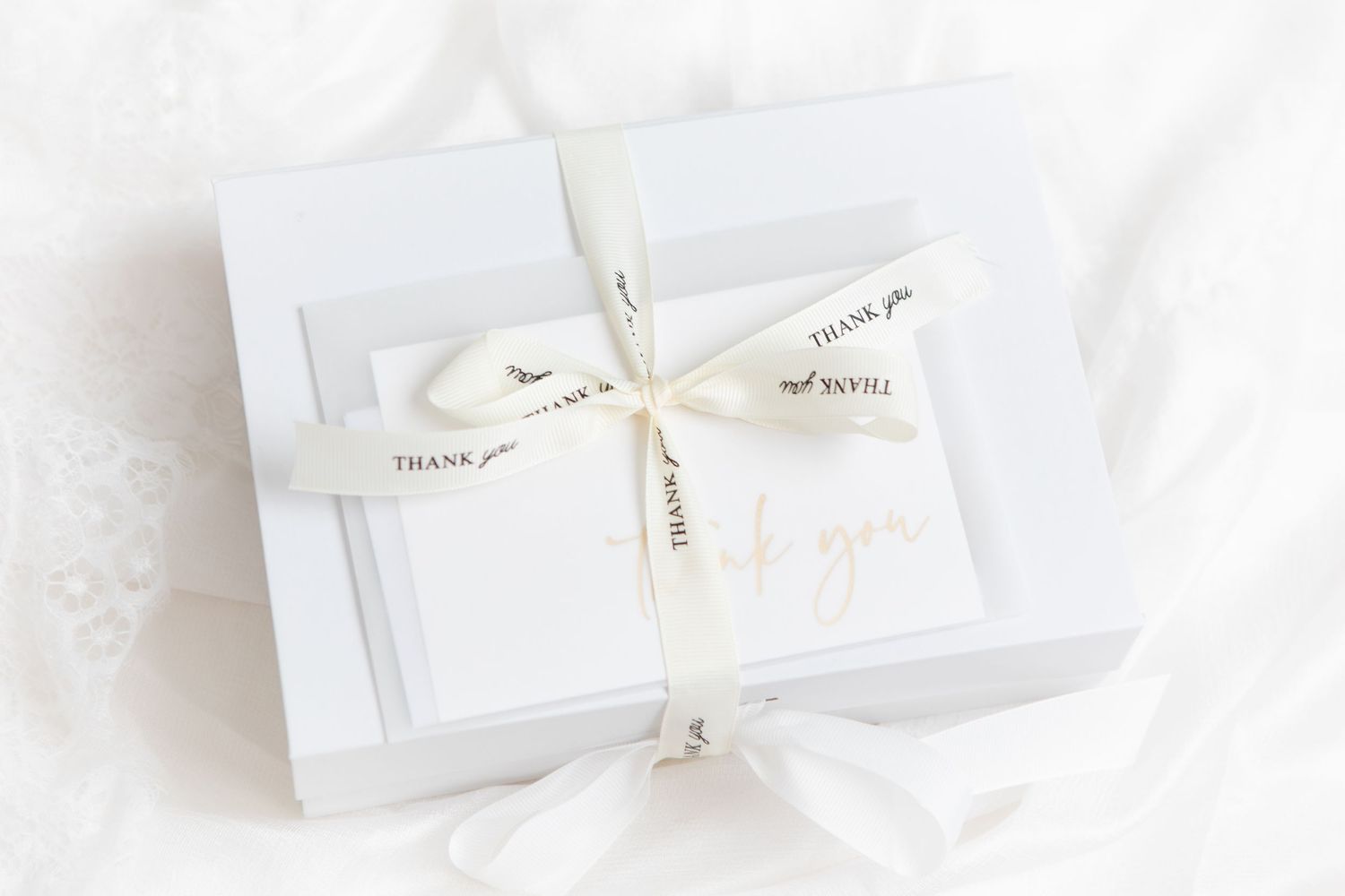 Elegant white jewelry or gift boxes with delicate ribbon bows arranged on a bright white background.
