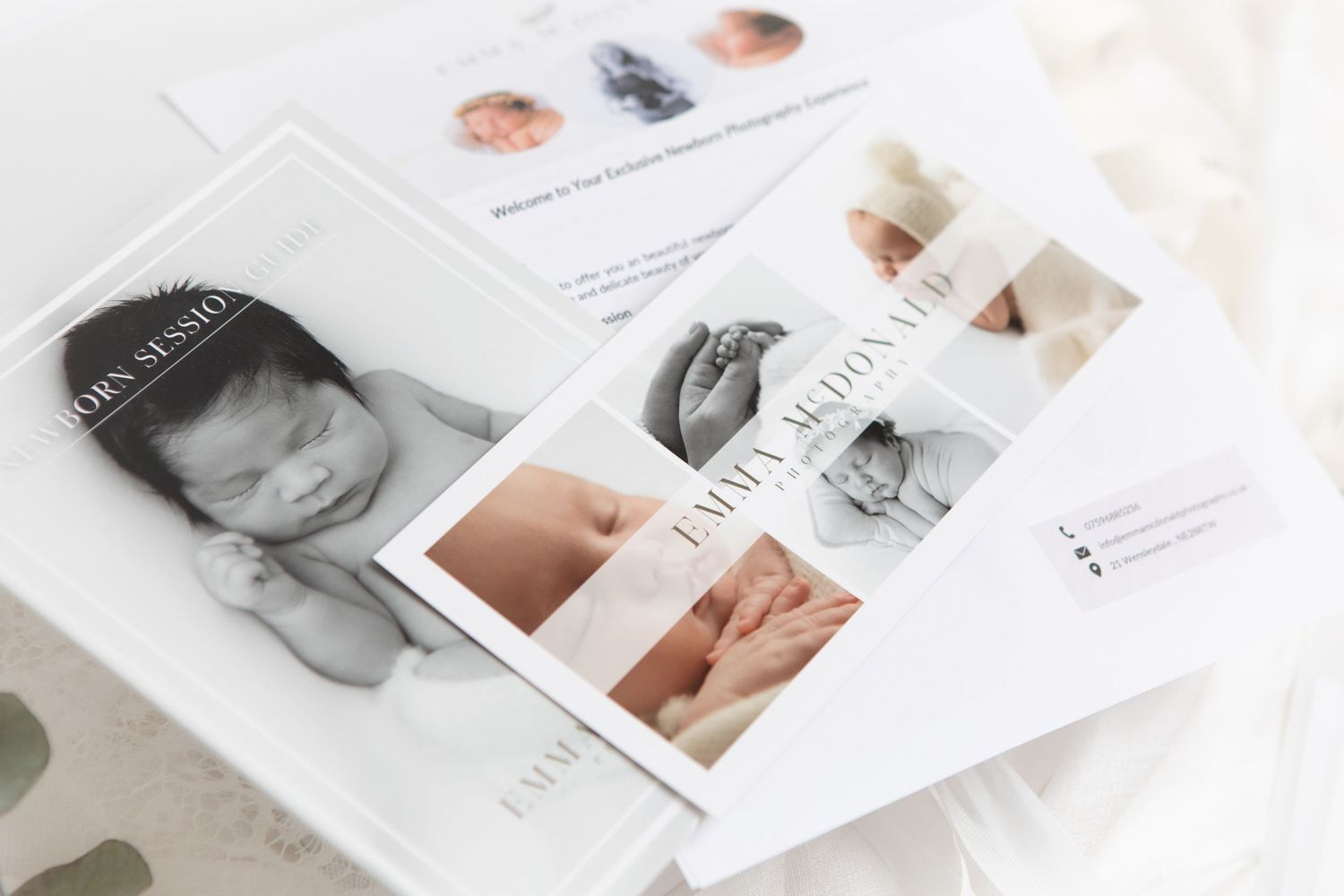 A collection of baby photographs laid out on a white surface showing monochromatic and color newborn prints.