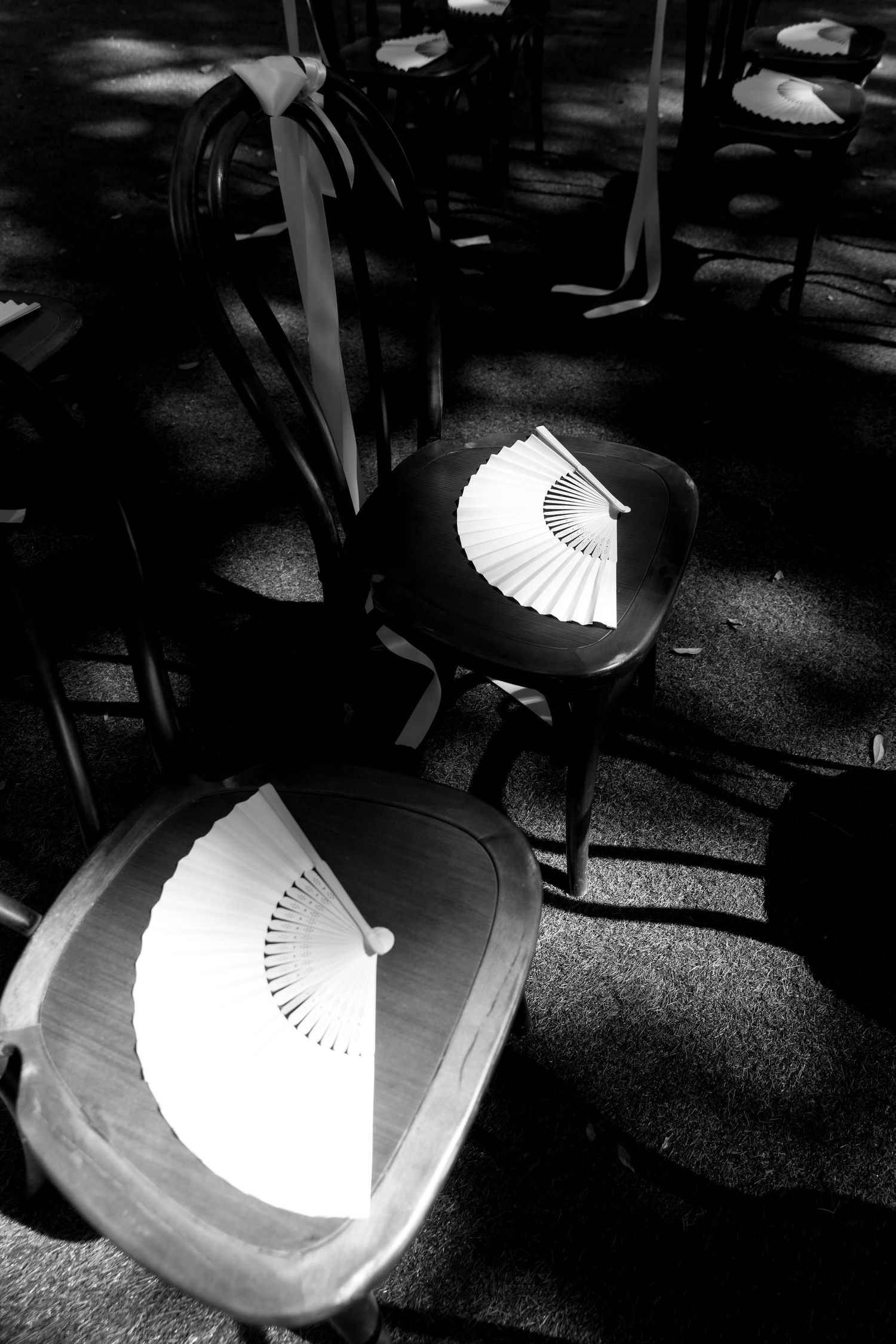 A series of black and white images showing a white paper fan casting dramatic shadows on a chair seat.