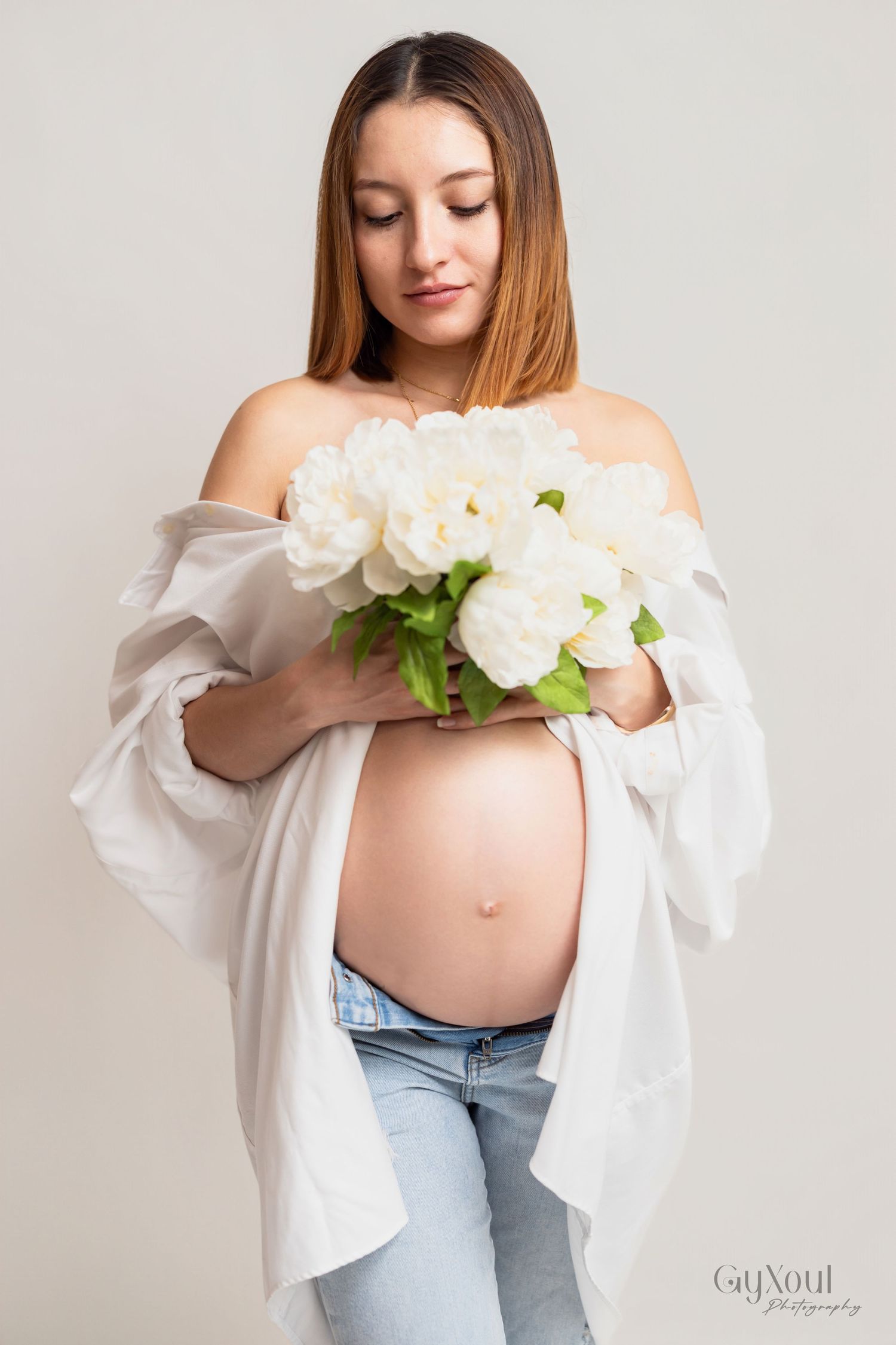 A maternity photo sequence showing a gentle reveal with light floral and white shirt styling against a neutral backdrop.