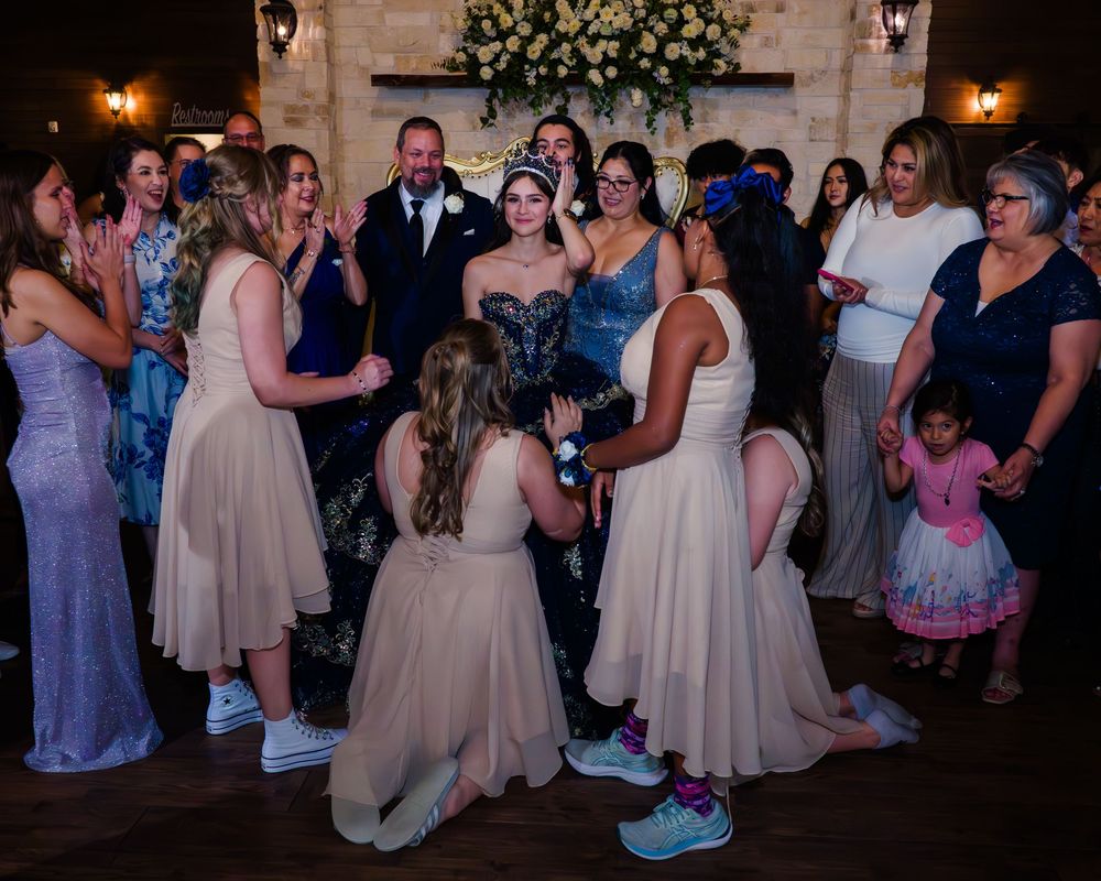 Wedding celebration with party guests gathered in formal attire at dimly lit indoor venue with festive atmosphere.