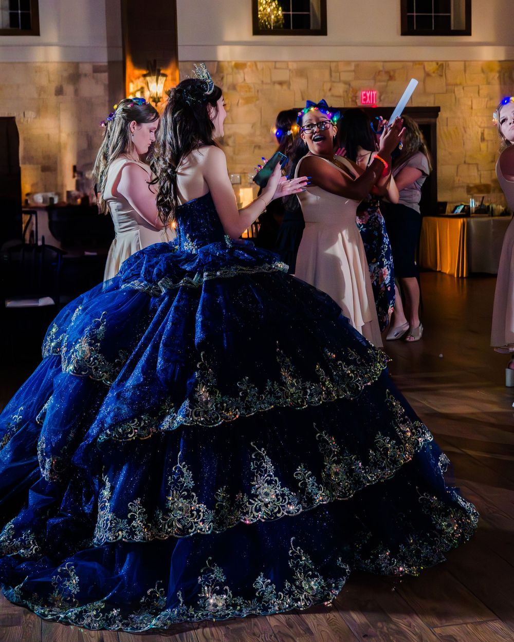 A person in a stunning royal blue ball gown with tiered lace details dances at an elegant evening celebration.