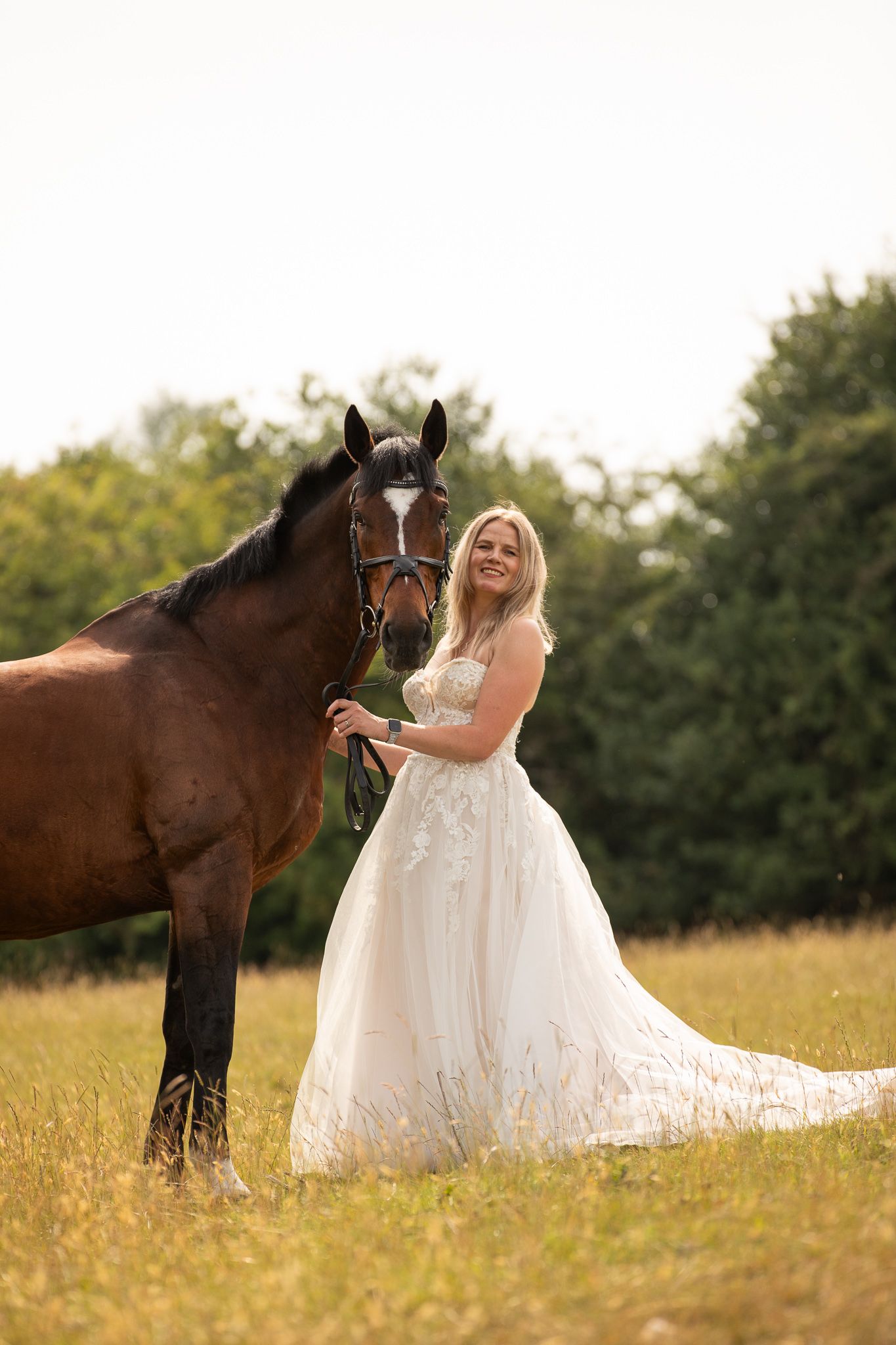 Young girl in denim overalls embraces a palomino horse in a sun-dappled forest setting.