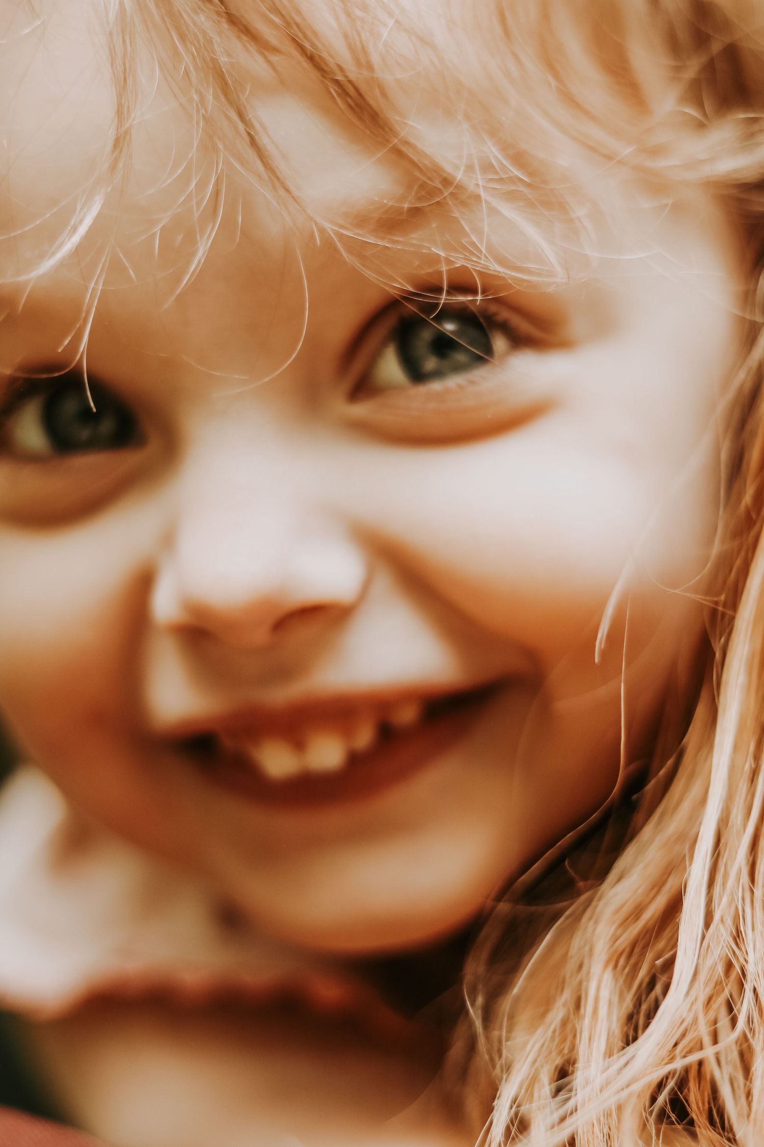 Close-up artistic portrait showing joyful expression and light hair.