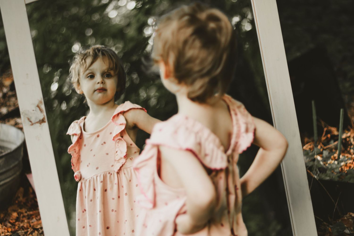 A playful moment captured on a white porch with greenery in the background.