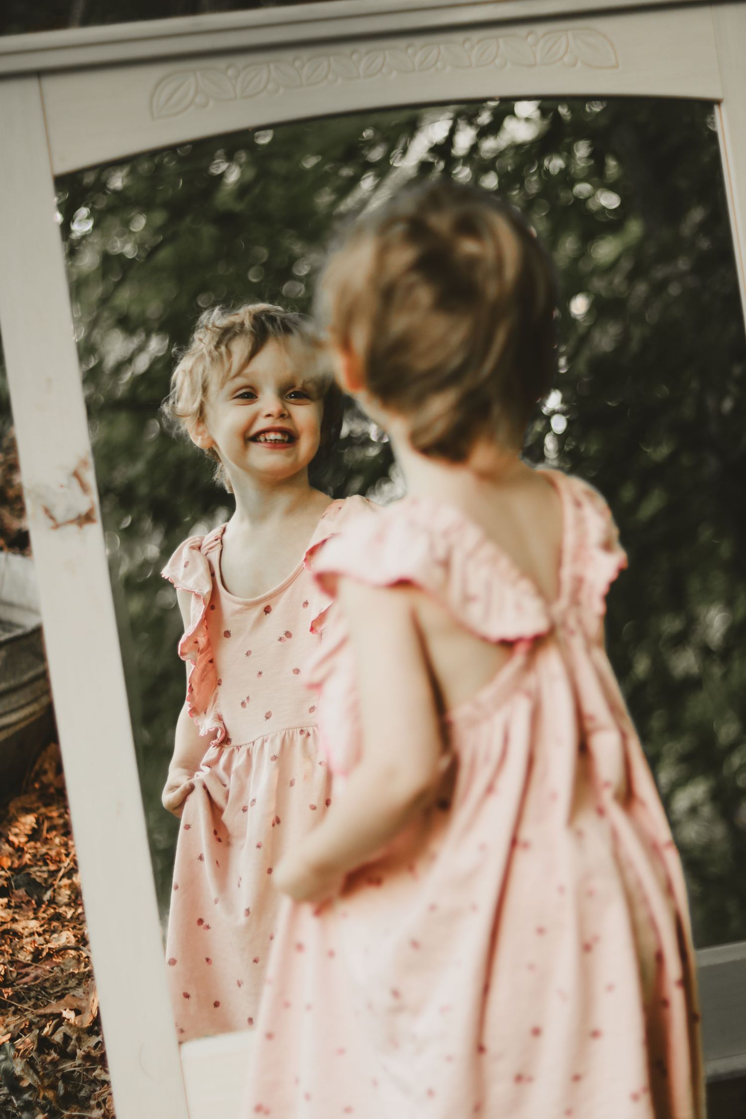 Mirror reflection on a white porch shows a delicate pink polka dot dress.