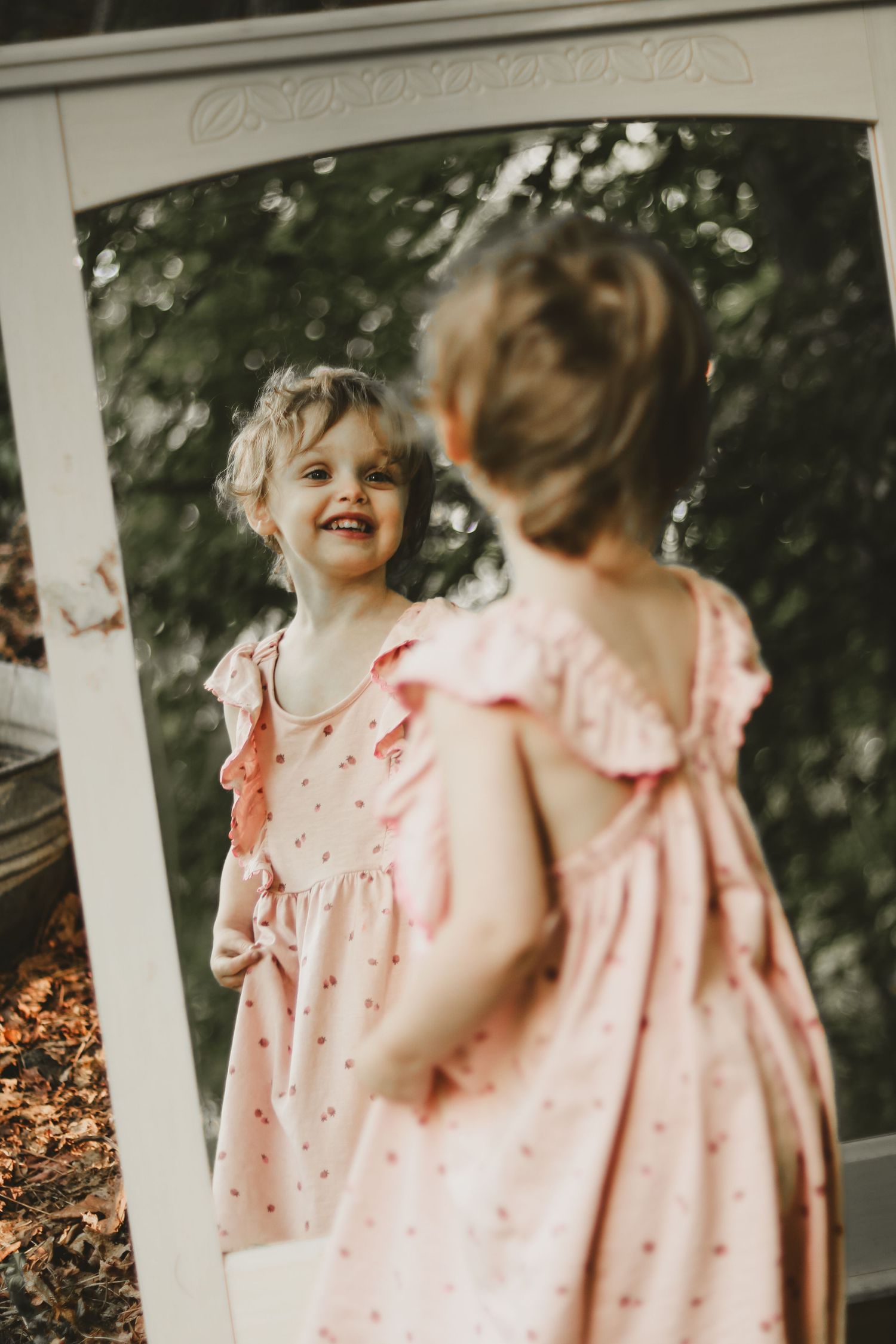 Joyful outdoor scene with a pink ruffled dress against white porch railings.