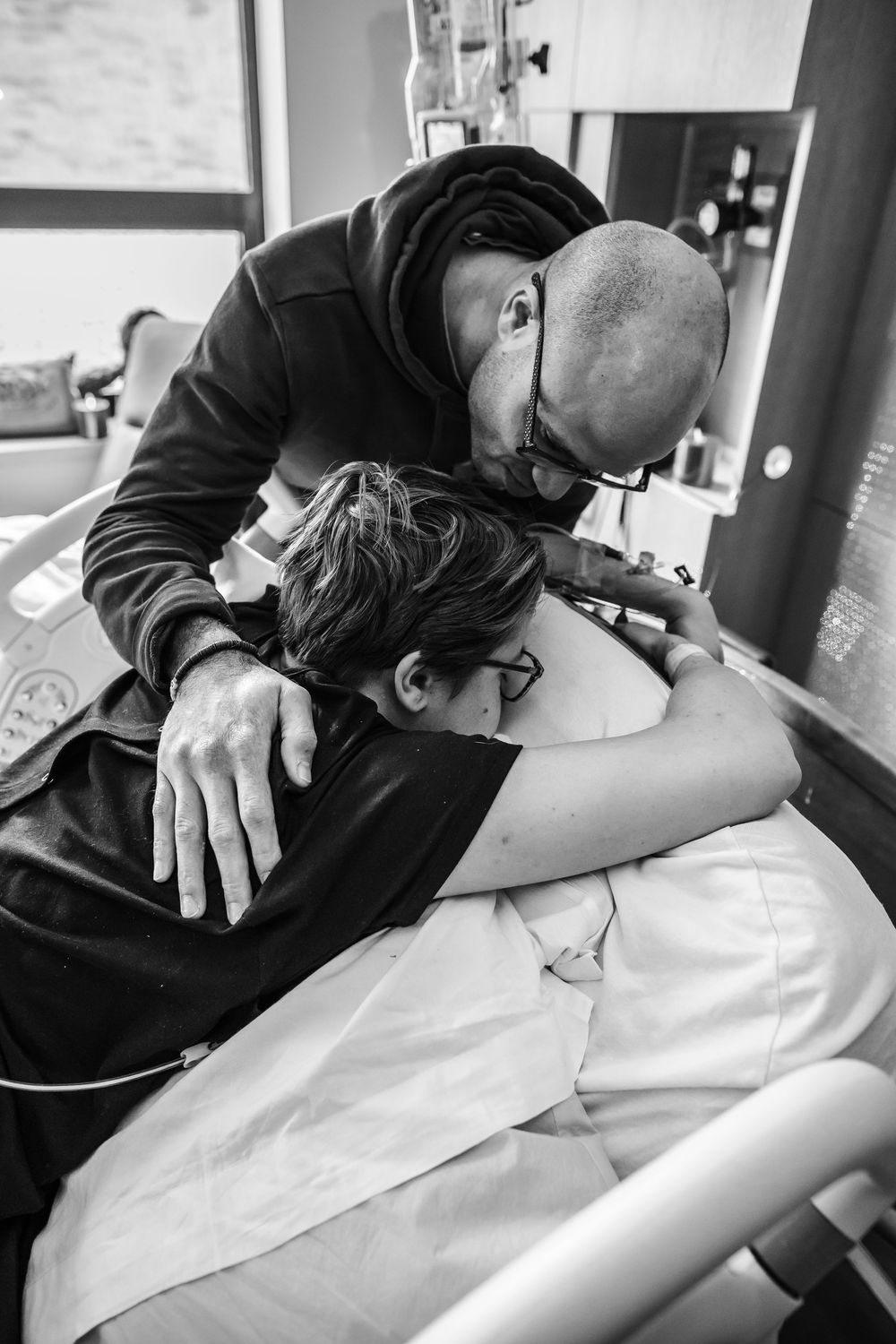 Medical professional providing care to patient in black and white hospital setting.