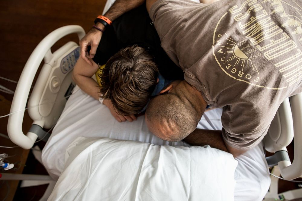 Medical care being provided to patient in hospital bed with monitoring equipment.