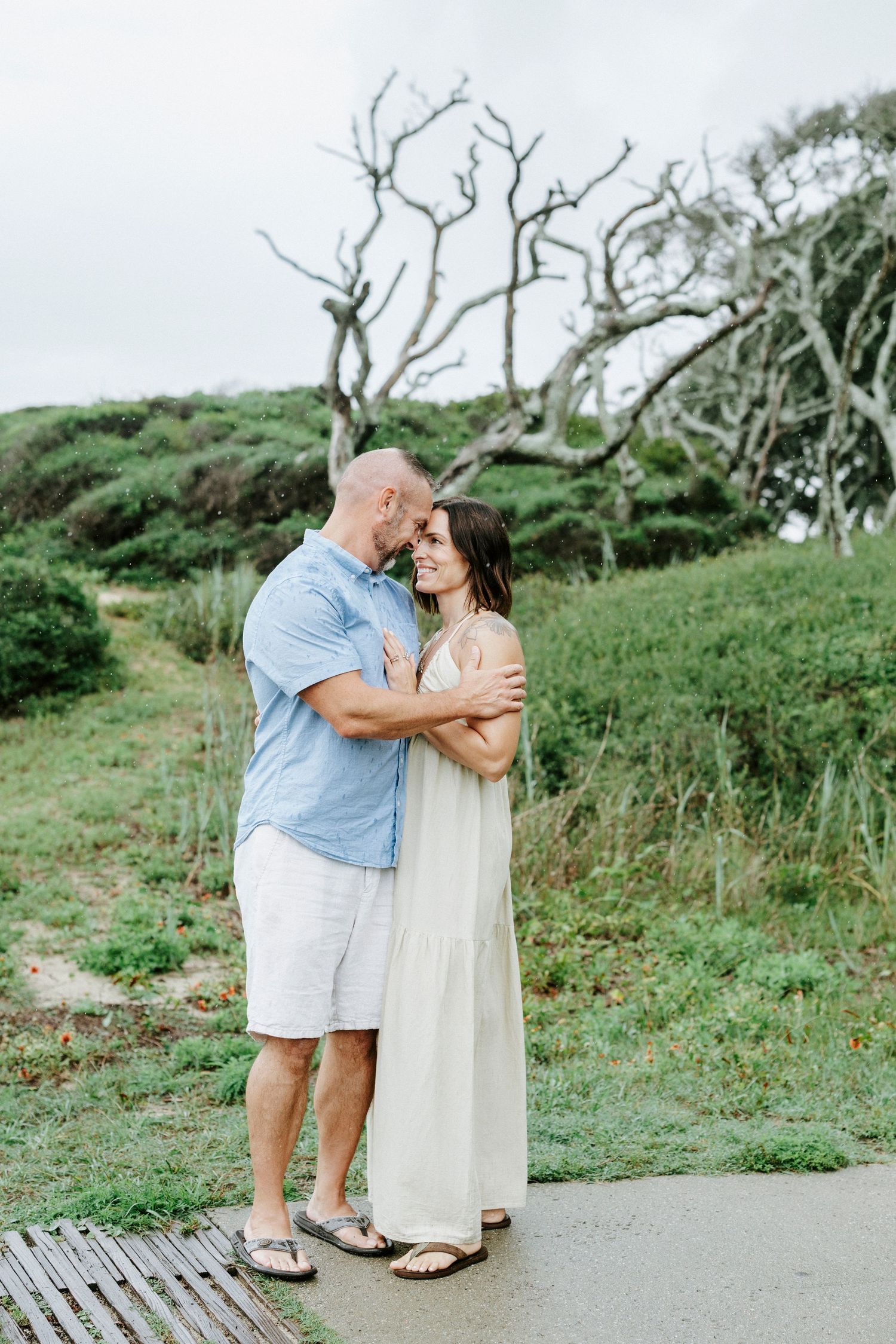 Sweet embrace shared on a coastal pathway with natural scenery in the background.