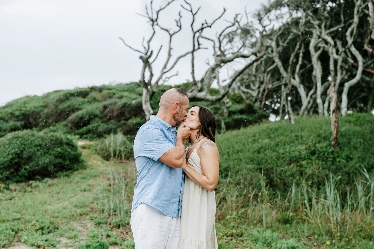Intimate moment shared on a coastal path surrounded by natural vegetation.