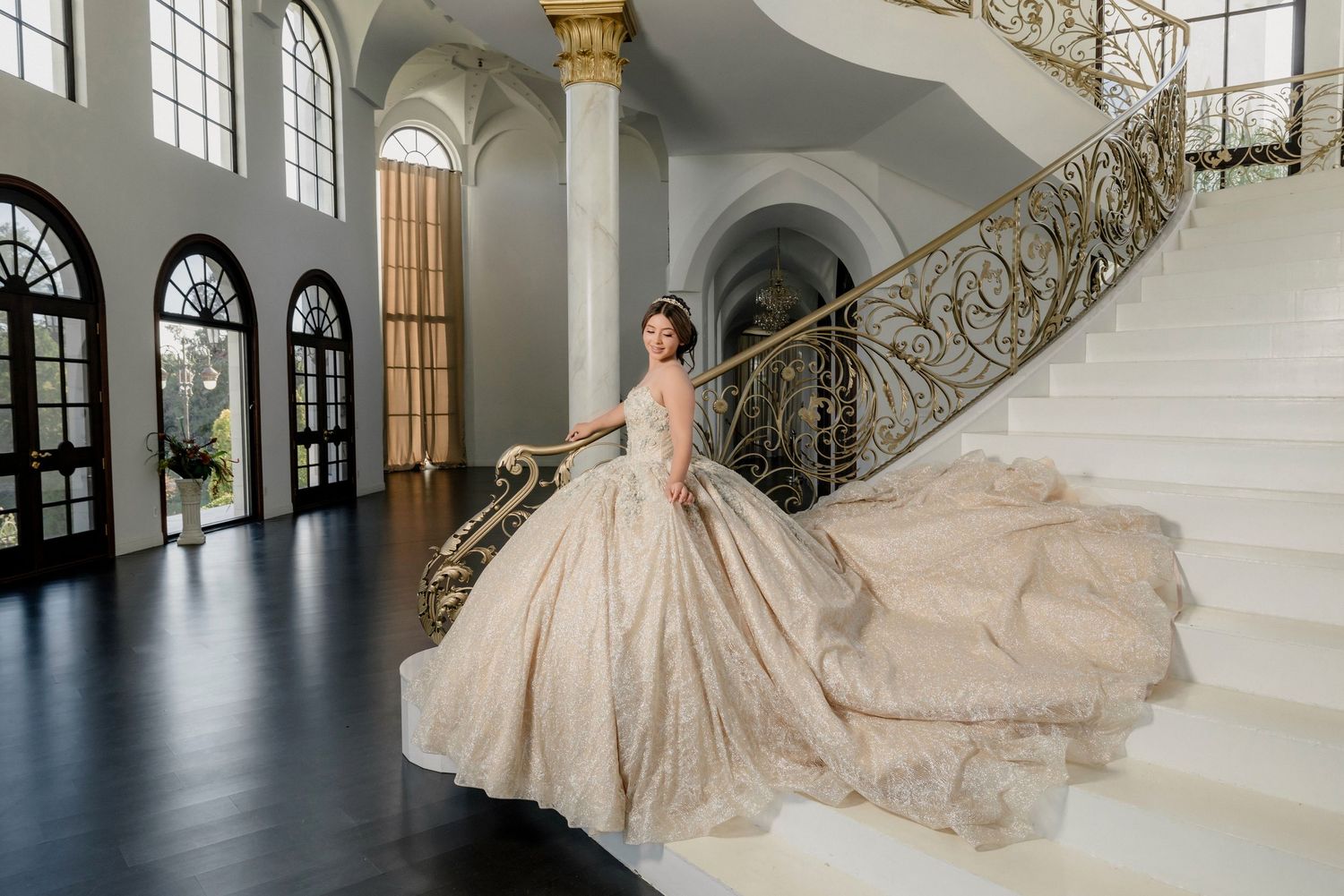 Luxurious bridal gown displayed in grand architectural setting with arched windows and ornate details.