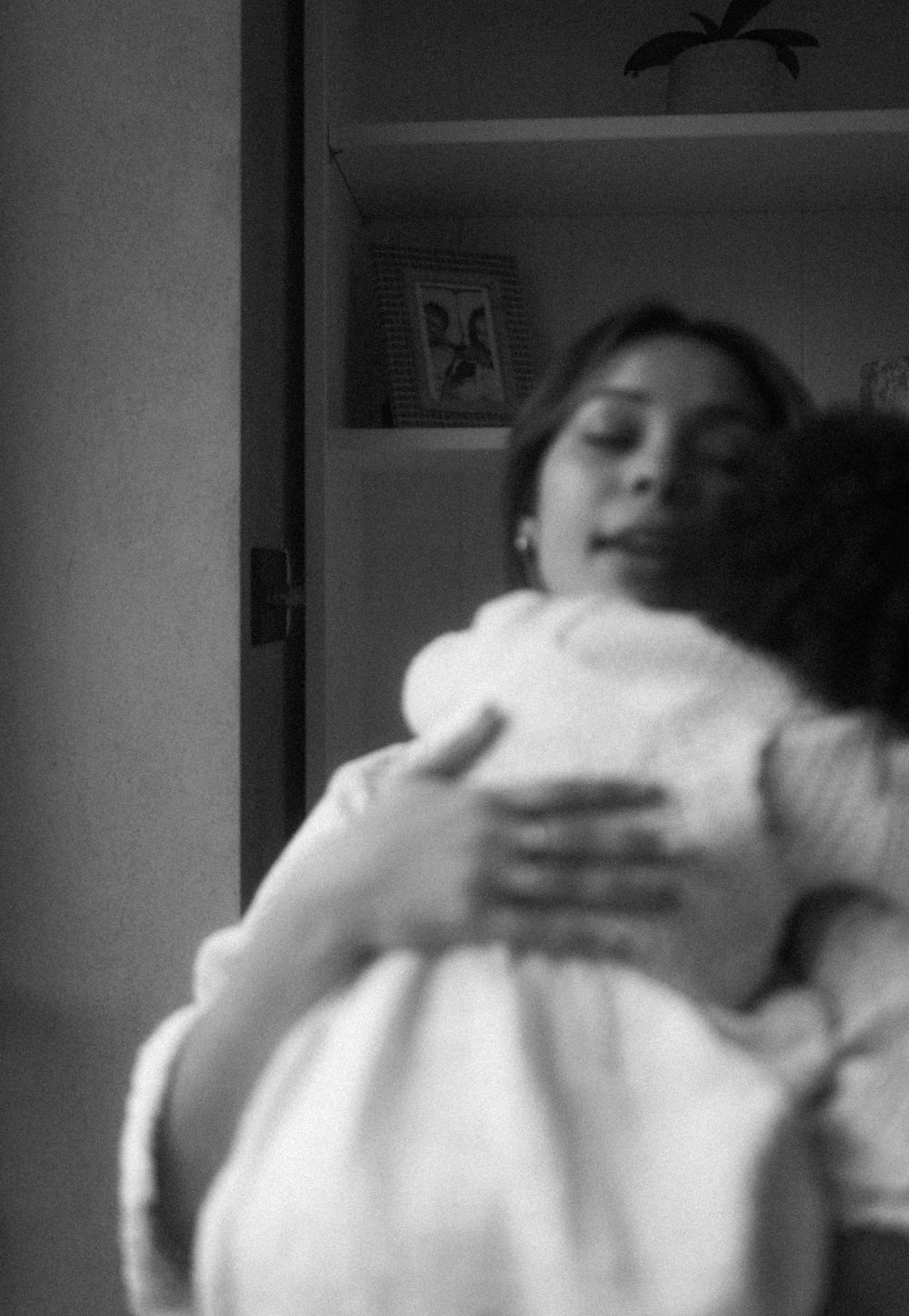 B&W out of focus photo of Mother & toddler daughter in an embrace. Family documentary photography