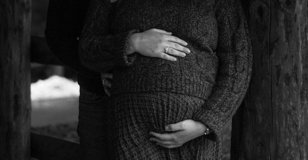 Pregnant mother clutching bump, documentary family photography
