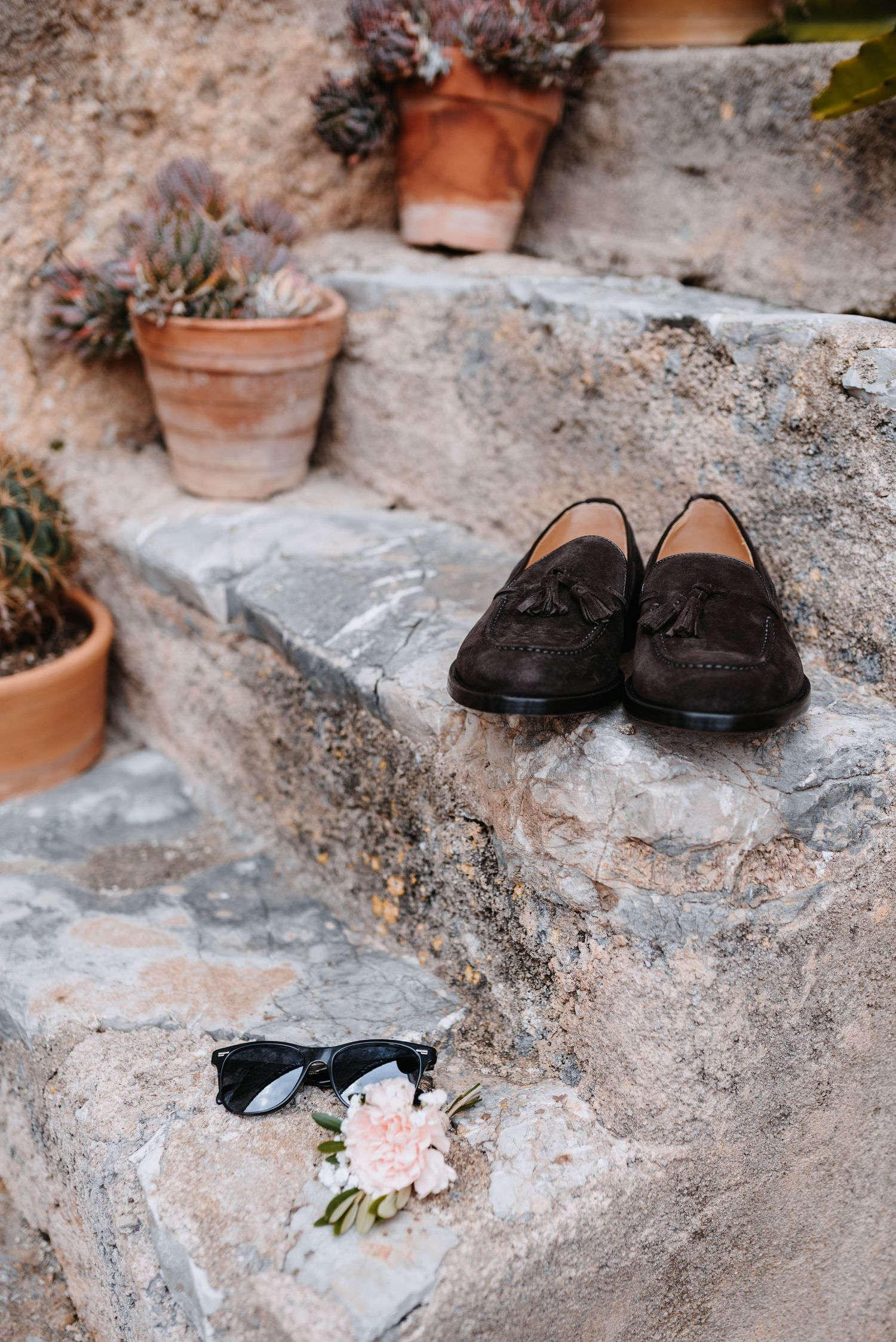 Dunkelbraune, Wildlederschuhe des Bräutigams. Fotografiert auf Steinstufen mit Tontöpfen im mallorquinischen Innenhof der Finca Xiclati.