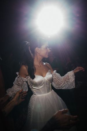 A sequence of silhouetted figures dancing in white garments against a dark background with bright light flares.
