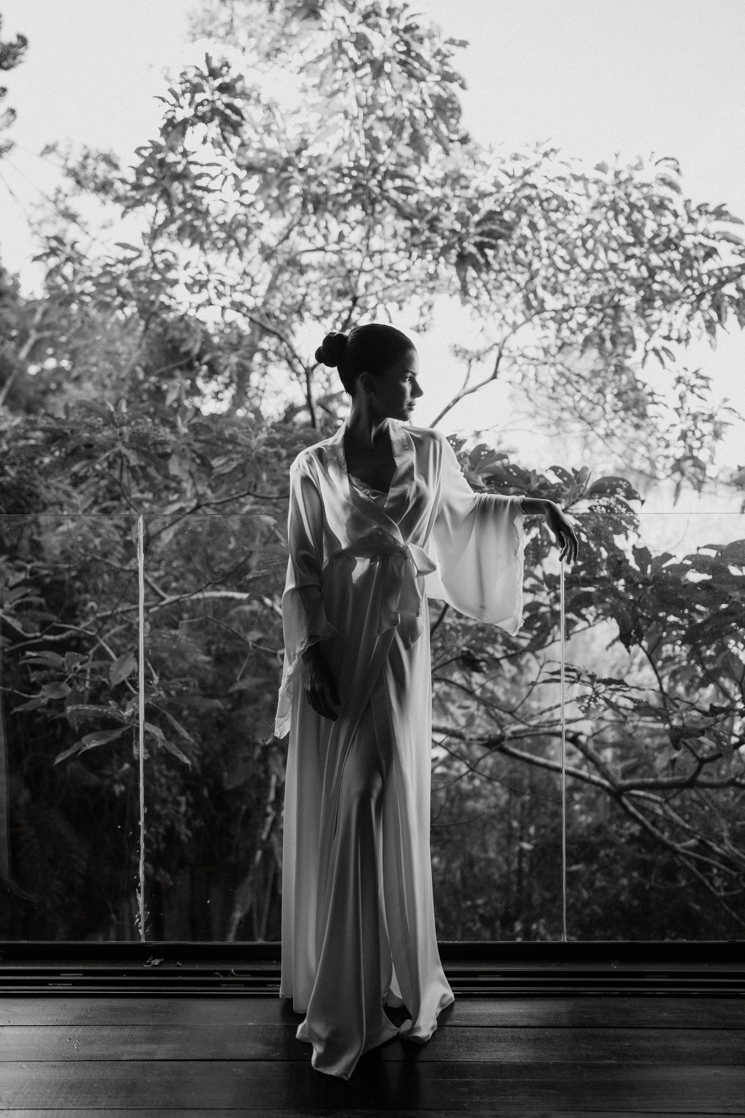 Multiple black and white photographs showing a figure draped in flowy white fabric near a window with natural light.