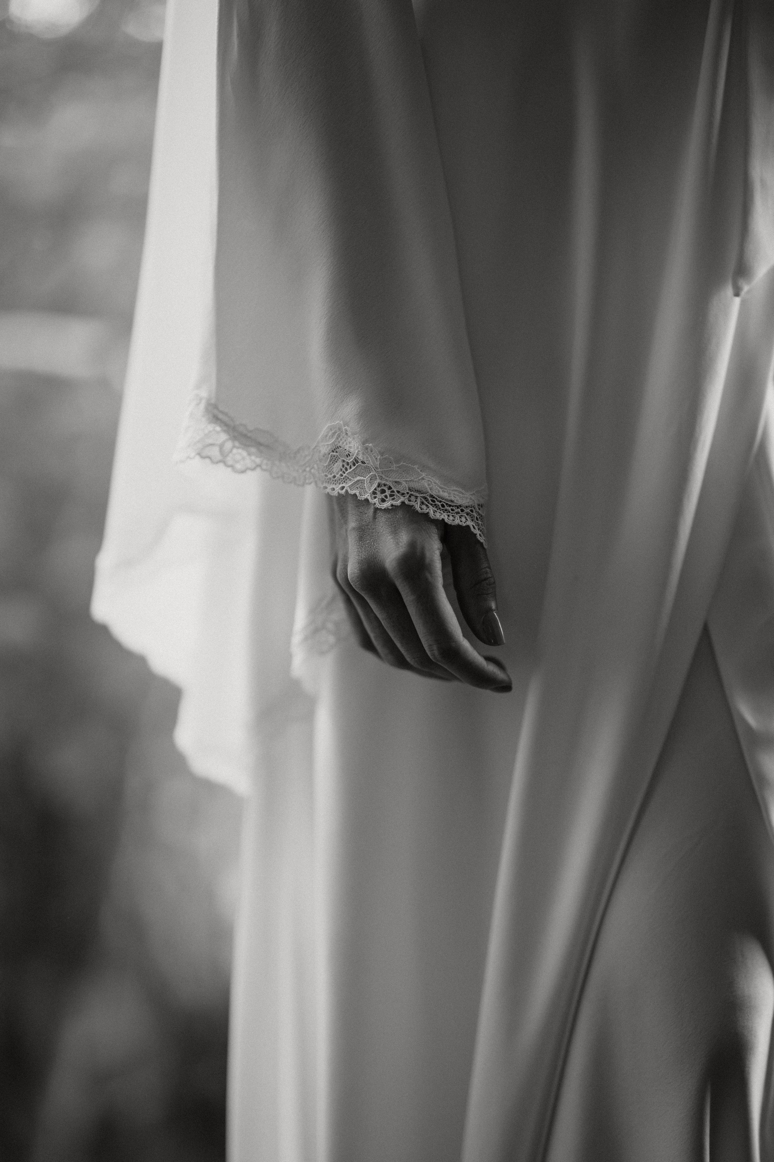 A collection of elegant white wedding dresses hanging on display, showing delicate lace and flowing fabrics.
