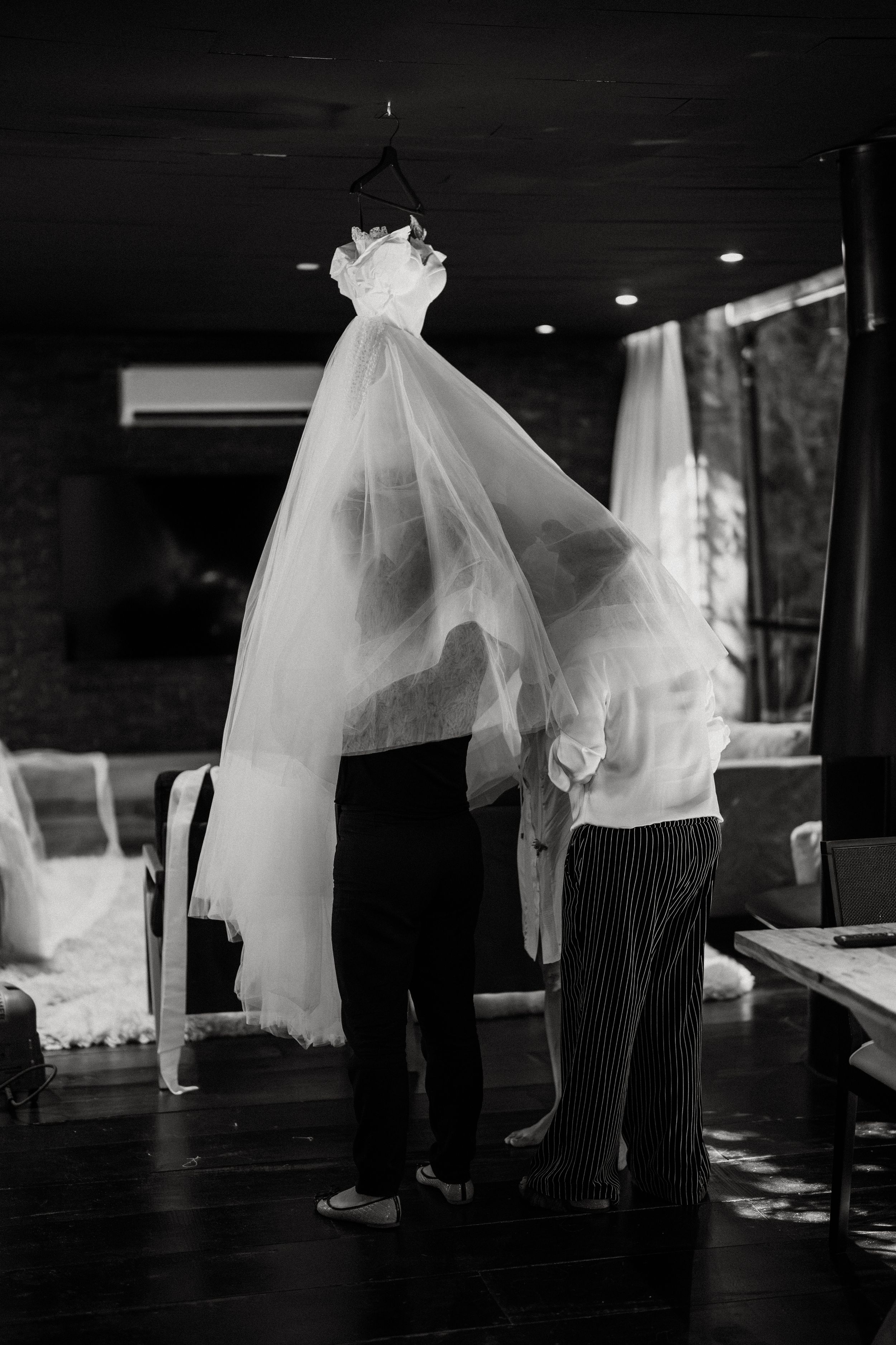 Black and white artistic photo of flowing white fabric and silhouettes creating a dramatic dance-like scene.