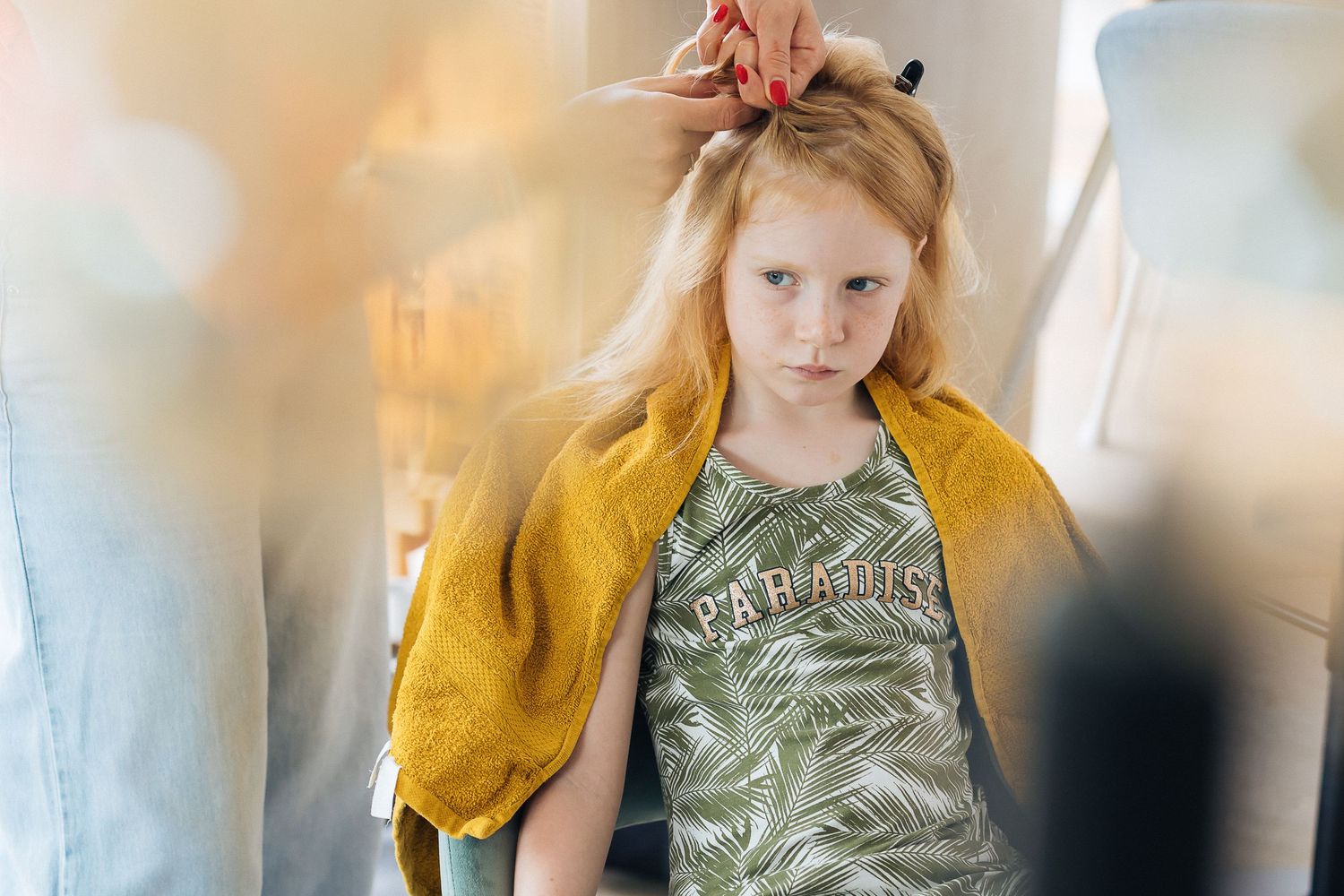 Child wearing yellow jacket and olive green clothing in softly lit interior.