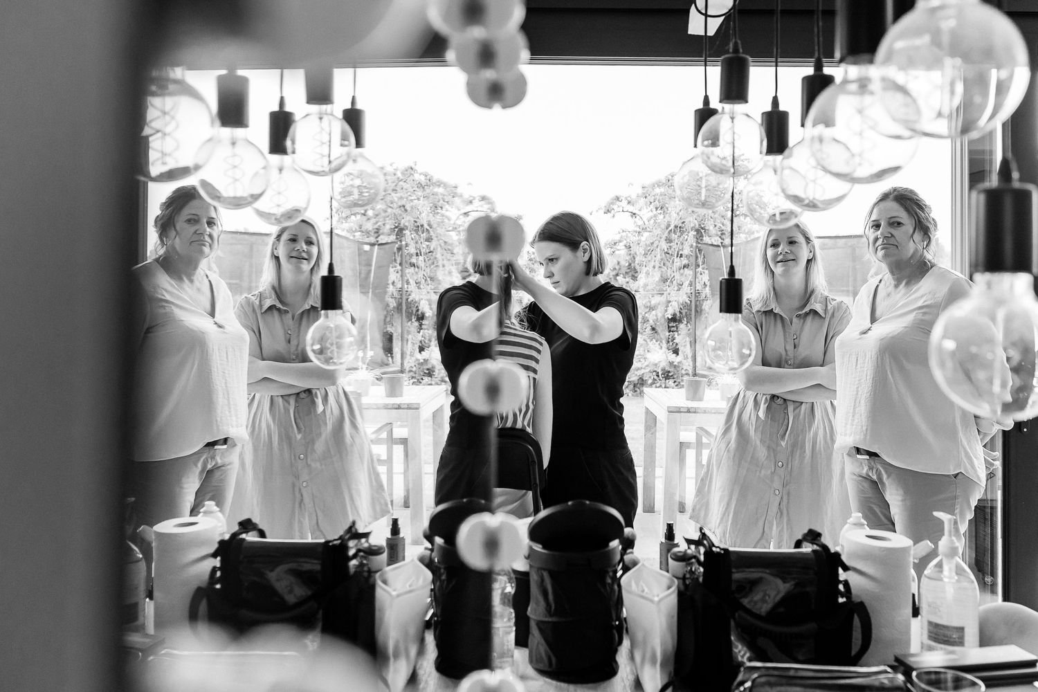 Black and white photo of wedding party gathered around couple at celebration.