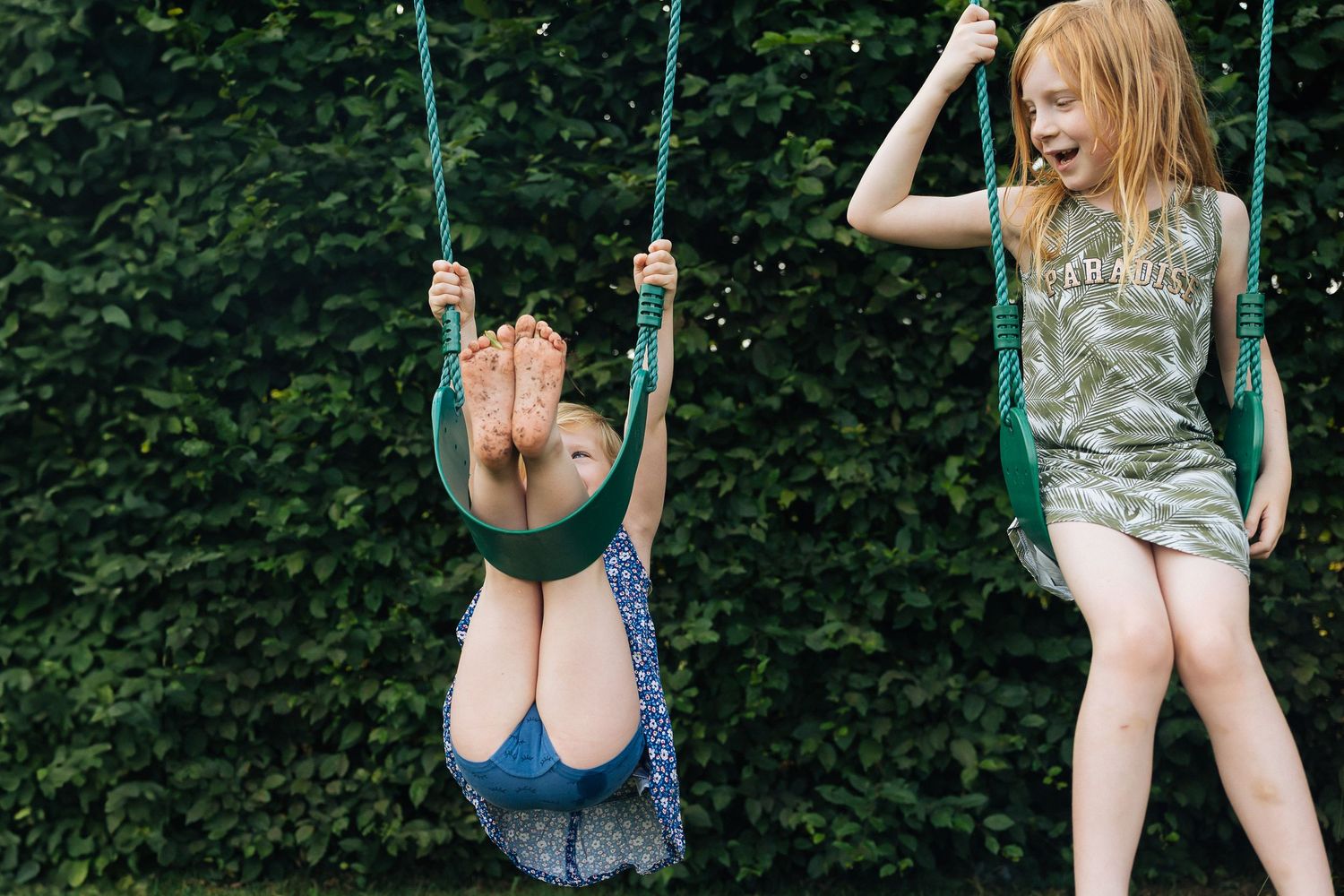 Children enjoying outdoor playtime on backyard swingset during summer.