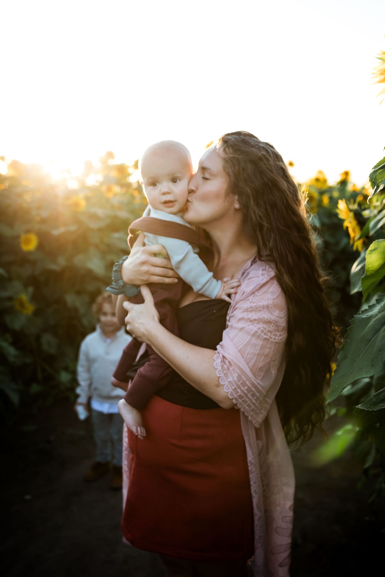 Beautiful motherhood golden hour photos at sunflower fields in Bowden Alberta by Calgary lifestyle photographer.