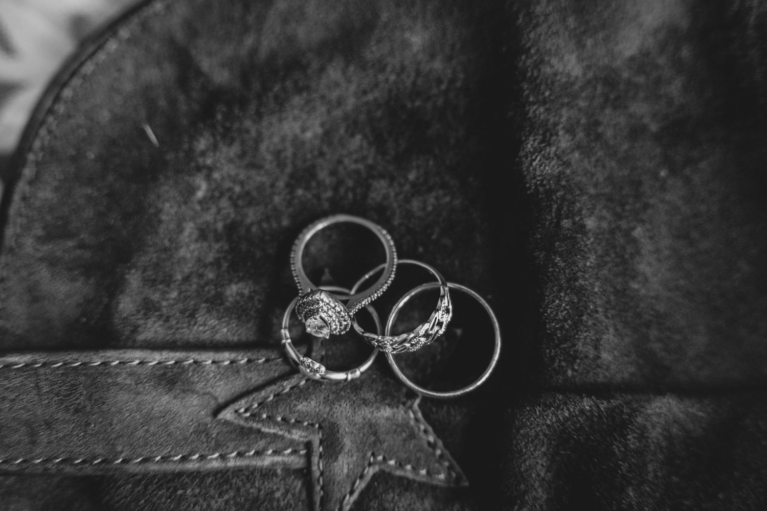 Wedding rings displayed on textured gray leather surface in black and white.