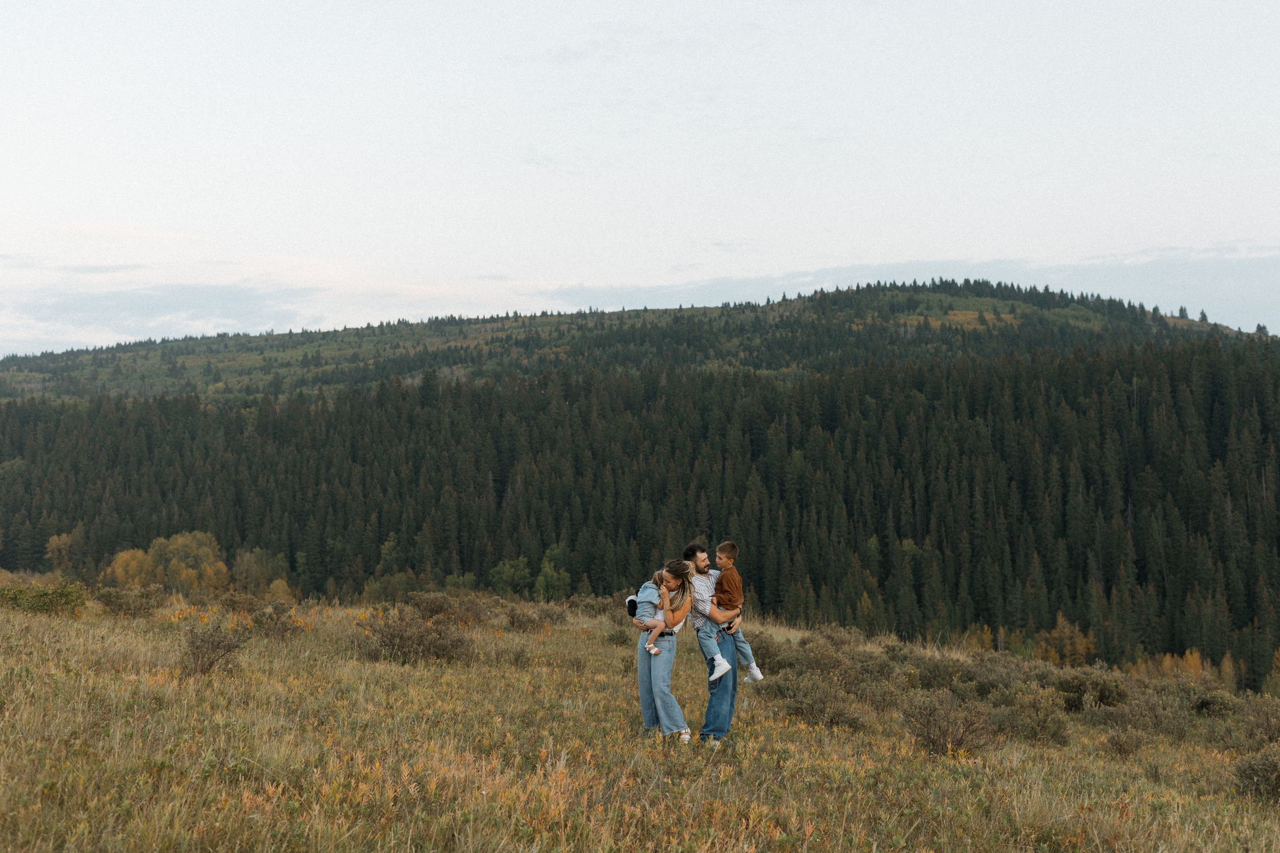 A romantic moment between two people embracing on a mountaintop overlooking a scenic lake and mountain landscape. Waterton National Park