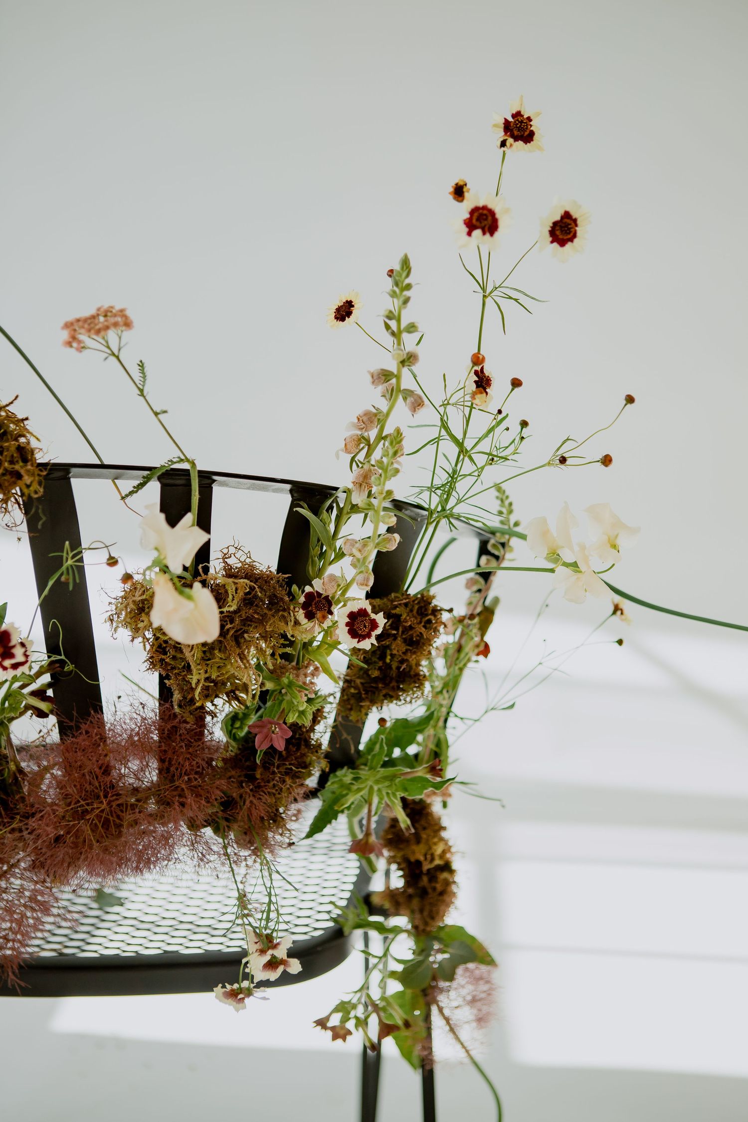 Artistic floral arrangement with wild red flowers and greenery in modern setting.