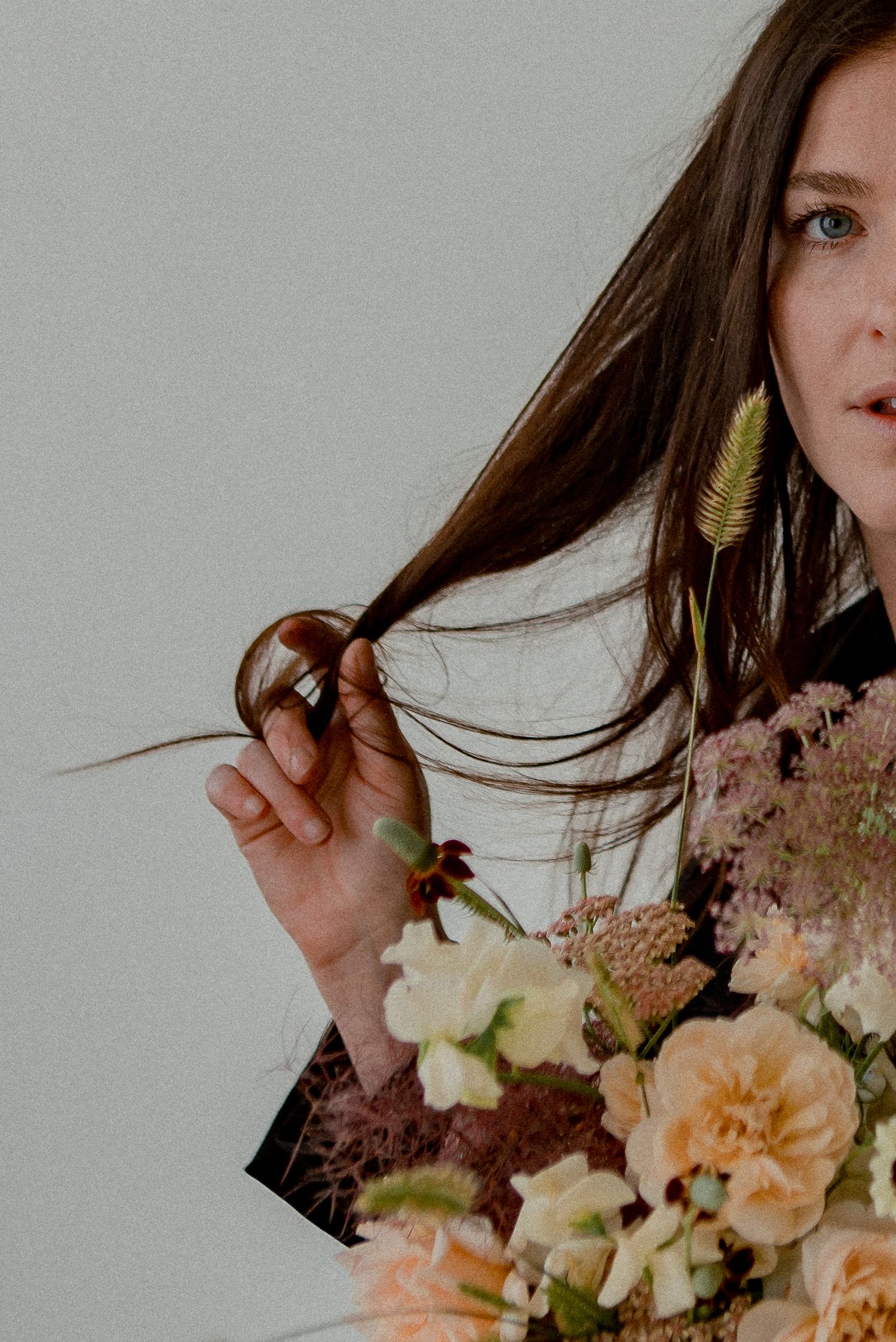 Close up portrait with long hair and delicate peach and cream floral bouquet.