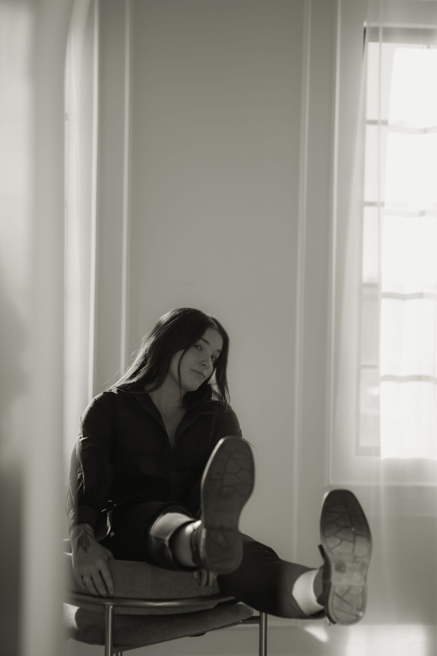 Black and white photo of a relaxed figure lounging in a chair by a window.