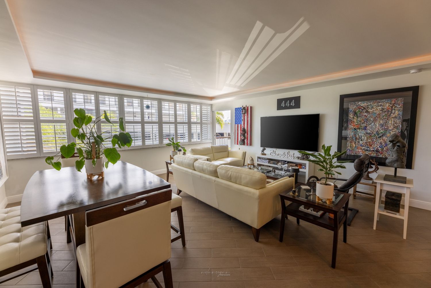 Modern open concept living room with plush seating, dining area, and large windows letting in natural light.