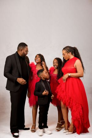 Family photoshoot with coordinating red outfits against a white studio backdrop.