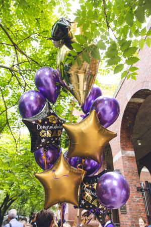 Purple and gold star balloons decorating an outdoor brick venue.