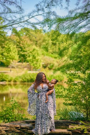 Two people in matching zebra print dresses share a joyful moment by a scenic pond.