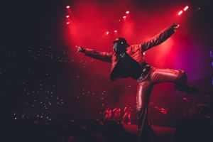 Dramatic concert performance silhouetted against red stage lighting and smoke effects.