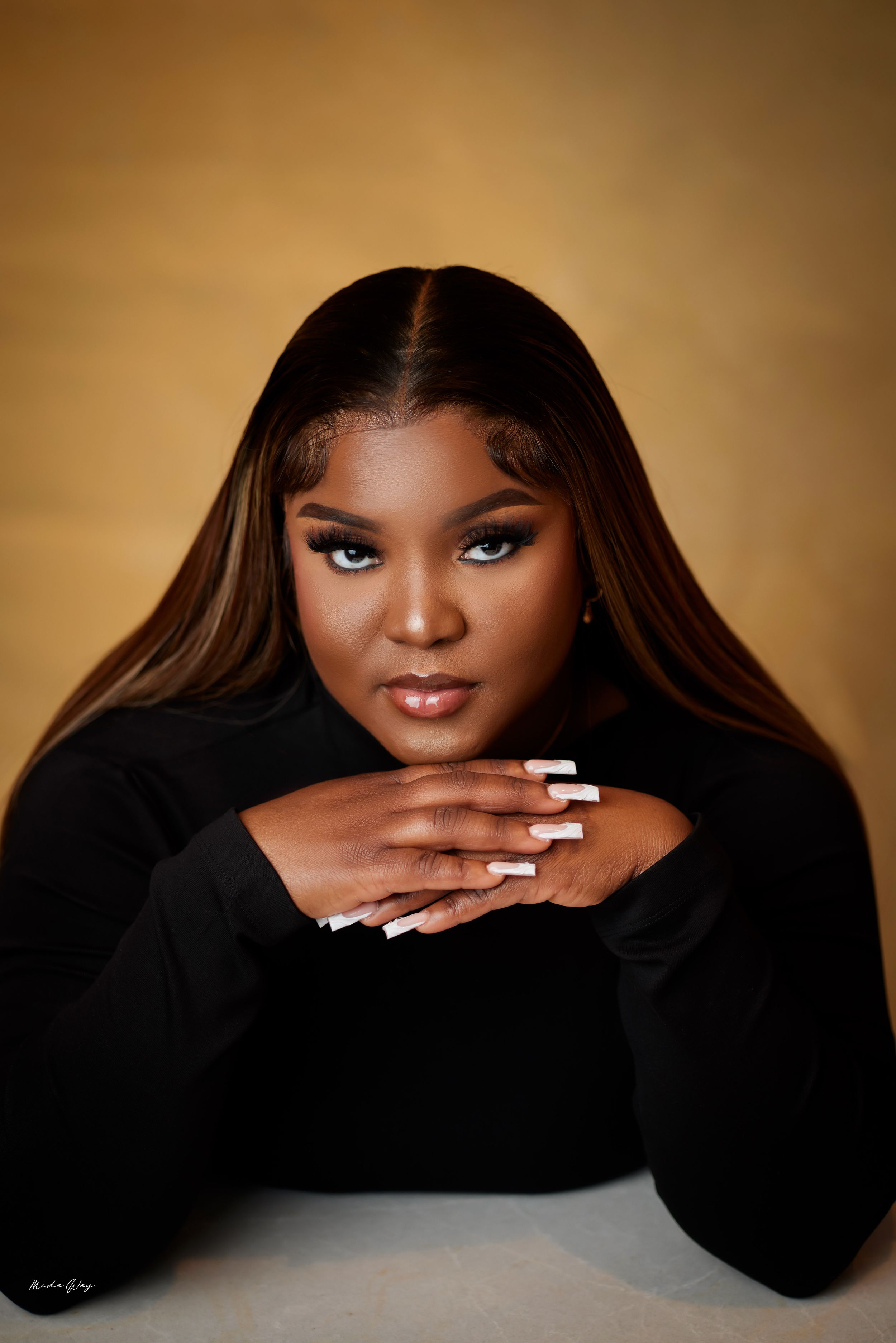 Studio portrait series in black clothing against a warm brown background with dramatic lighting.