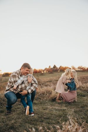 Couple embraces in a romantic moment while sitting in an autumn field at sunset.