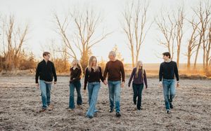 A group of people walking through a rustic outdoor setting at sunset in casual attire.