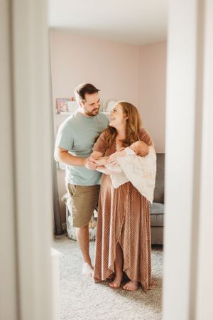 Couple sharing tender moment with newborn baby in nursery.
